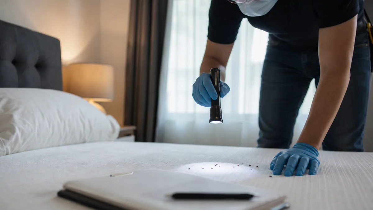 Technicien inspectant un matelas avec lampe et documents d’assurance habitation sur une table