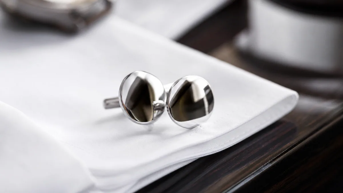 Gros plan de boutons de manchette ronds en métal poli miroir sur une chemise blanche