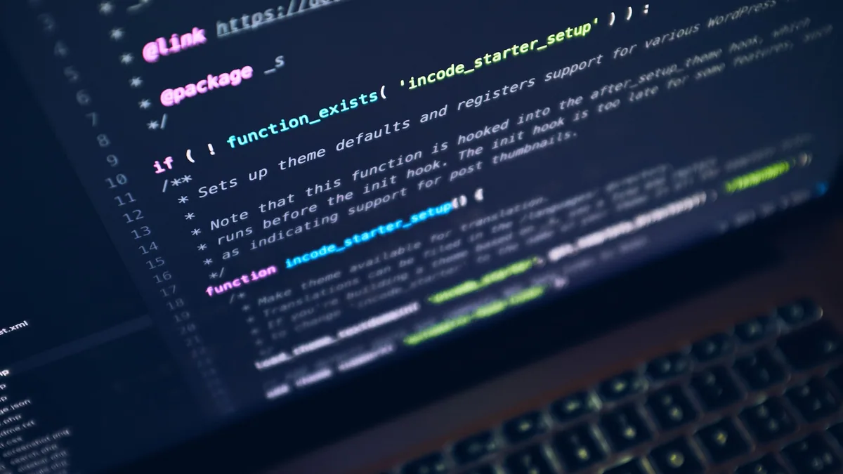 Personne utilisant une application de programmation sur smartphone devant un ordinateur portable
