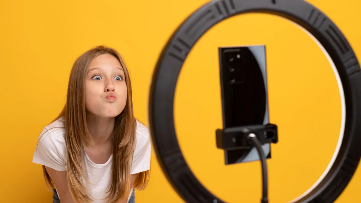 Créatrice filmant une vidéo verticale avec un smartphone devant un bureau lumineux