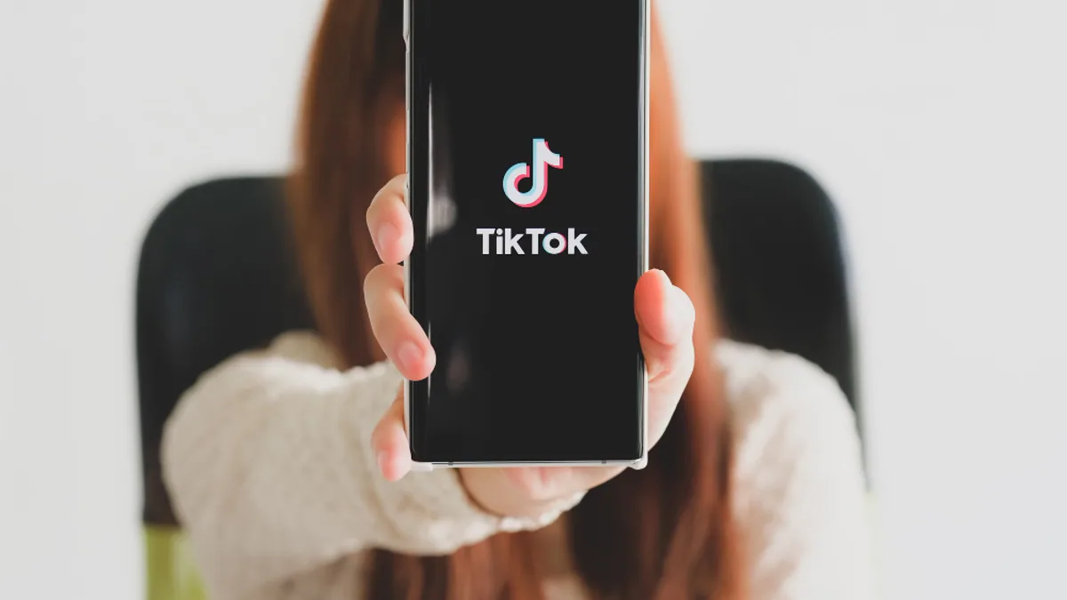 Smartphone affichant l’interface TikTok avec une personne filmant une vidéo verticale