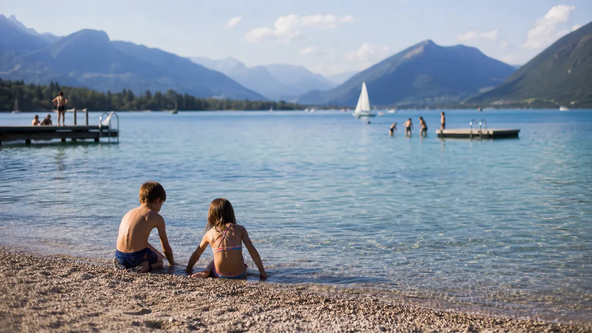Famille avec enfants à vélo près des eaux turquoise du lac d’Annecy et des montagnes