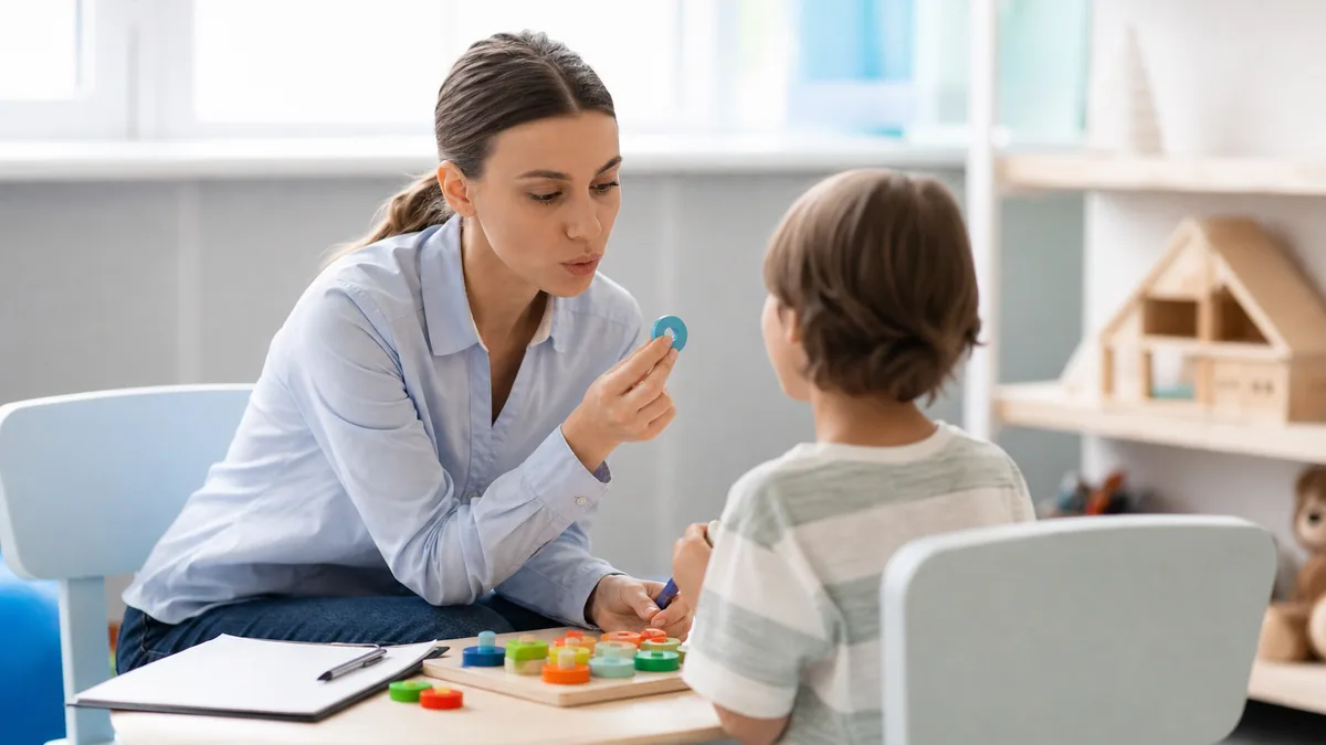 Orthophoniste échangeant avec un enfant autiste à l’aide de pictogrammes sur une table