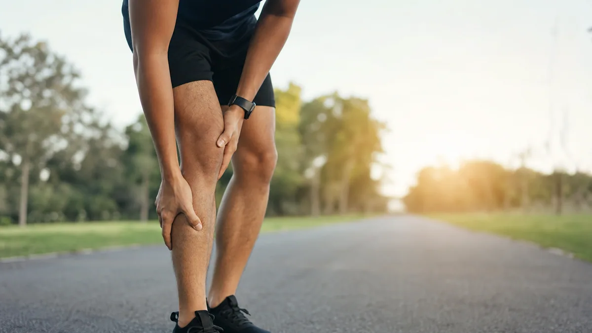 Personne s'étirant les jambes après une séance de sport en extérieur
