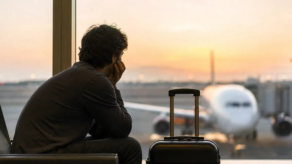 Voyageur fatigué consultant l'heure sur son téléphone dans un aéroport de nuit