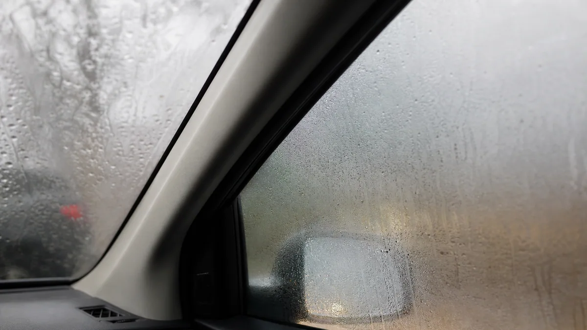 Vitre latérale de voiture entièrement couverte de buée et de gouttes de condensation
