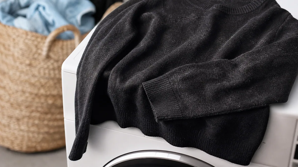 Pull noir délavé et grisonnant posé à côté d'un pull noir profond, sur un fond clair
