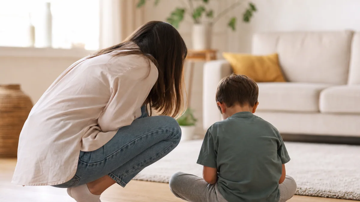 Parent accroupi face à un jeune enfant en pleine crise, dans un salon lumineux