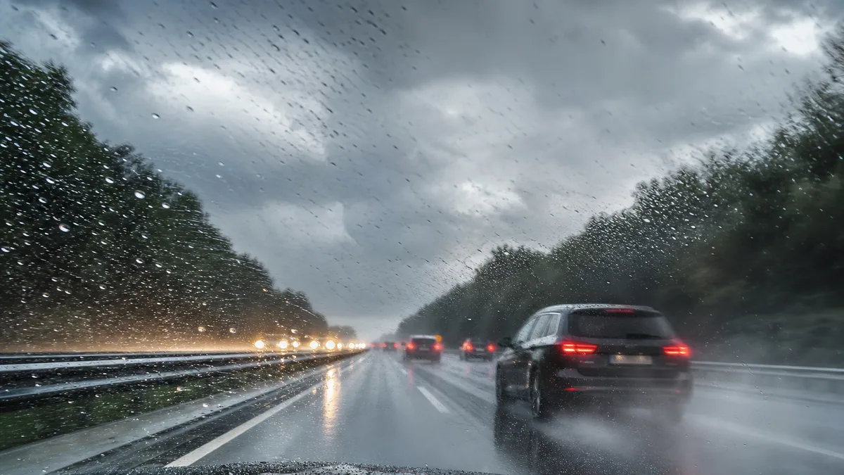 Voiture roulant sur une autoroute mouillée sous une pluie battante, phares allumés