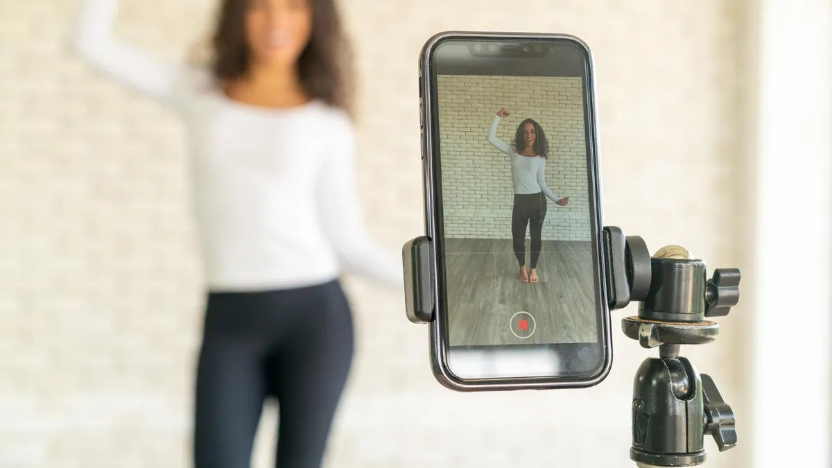 Créatrice filmant une vidéo TikTok avec smartphone sur trépied et tableau de statistiques