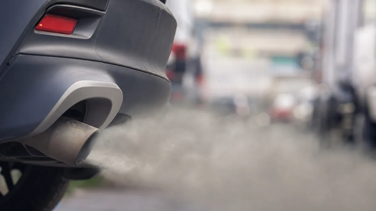 Arrière d’une voiture rejetant des gaz d’échappement sur une route urbaine